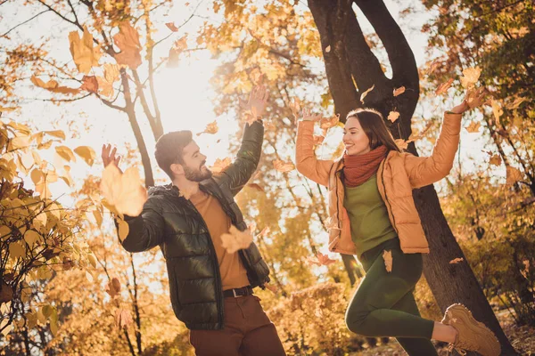Låg vinkel visa foto av positiva par kasta blad i oktober stadspark under solnedgången glans bära rockar — Stockfoto