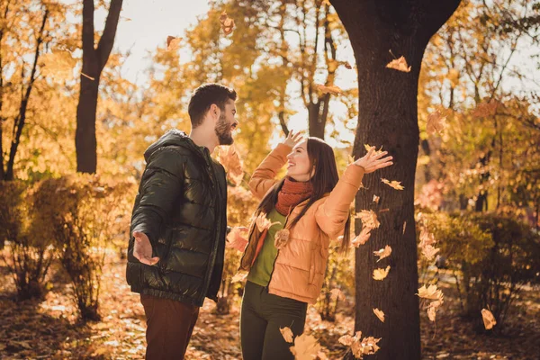 Φωτογραφία του θετικού χαρούμενου ζευγαριού άντρας και κορίτσι ρίχνουν πορτοκαλί φύλλα στην πόλη έξω από το πάρκο φορούν παλτό Seacon — Φωτογραφία Αρχείου