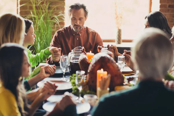 Full family ask god grace prayer hold hands thanks giving dinner tradition sit table turkey dish living room indoors