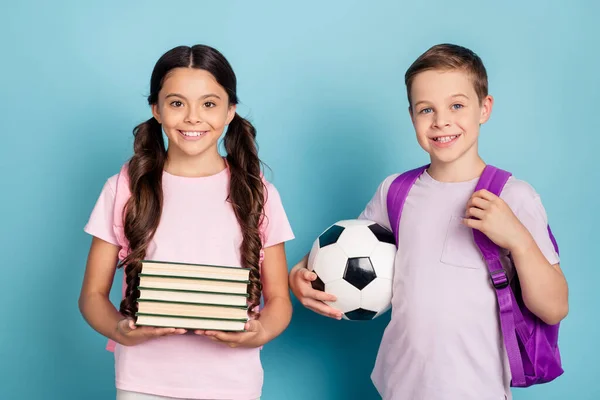 スマートAレベルの学生は、 9月1日の学校の概念を準備します。2人の小さな子供女の子男の子ホールドサッカーボール杭本楽しいレッスン勉強服tシャツリュックサック隔離された青の色の背景 — ストック写真