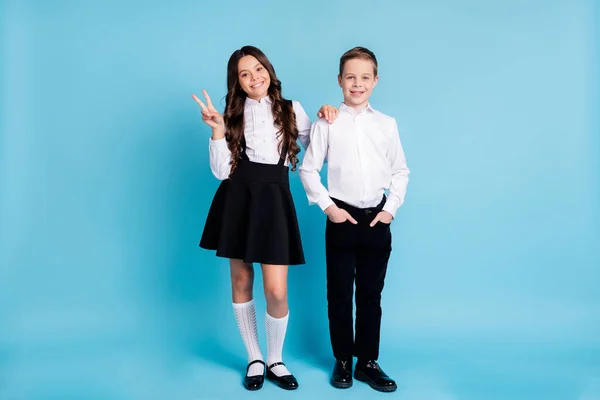 Привет, школьница. Полная длина фото двух девочек мальчик модель школьников одноклассники сестра брат показать V-знак носить однородную белую рубашку черные брюки платье обувь изолированный синий цвет фона — стоковое фото
