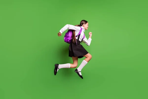 Foto retrato de menina correndo para a escola vestindo meias brancas saco roxo isolado no fundo de cor verde vívido — Fotografia de Stock