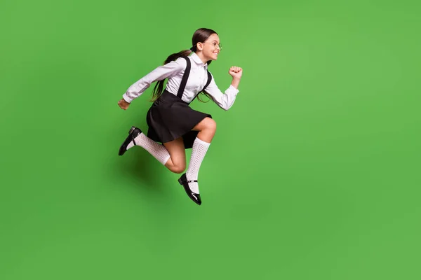 Foto portret van meisje rennen naar school springen omhoog geïsoleerd op levendige groene gekleurde achtergrond — Stockfoto