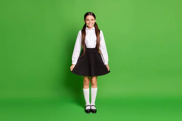 Retrato fotográfico de una joven colegiala sosteniendo demostrando su falda aislada sobre un fondo de color verde vivo — Foto de Stock