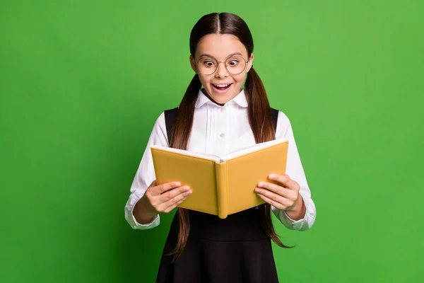 Photo of cute lovely small lady in front of blackboard hold read book excited find new curious information prepare share classmates wear white shirt glasses isolated green color background — Stock Photo, Image