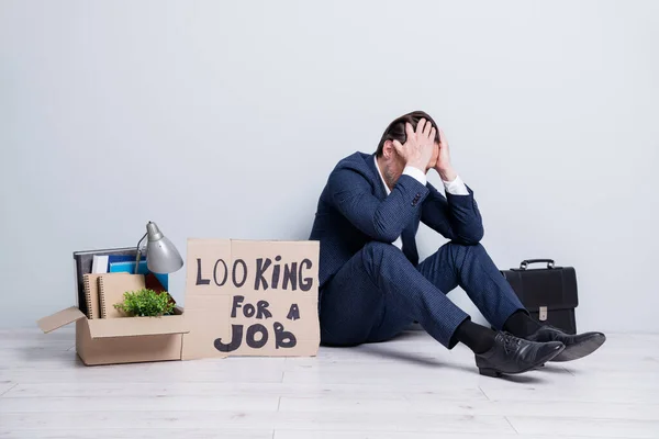 Full size photo of loser mature guy jobless business man handmade placard need work sit floor briefcase belongings box unsuccessful career crash wear suit shoes isolated grey background — Stock fotografie