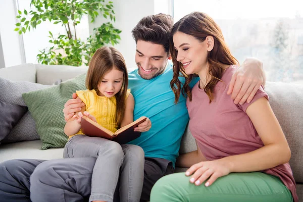 Foto de tres personas sentarse acogedor sofá pequeña chica id leer libro padre madre escuchar disfrutar en casa en el interior — Foto de Stock