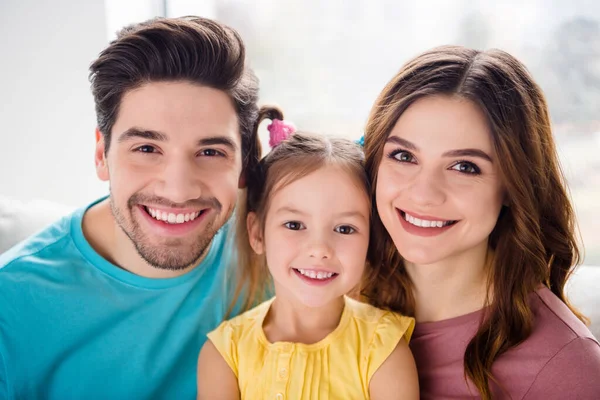 Nahaufnahme Foto von entzückenden Familie Mutter Vater kleines Mädchen Kind Blick in die Kamera zahmes Lächeln im Haus drinnen — Stockfoto