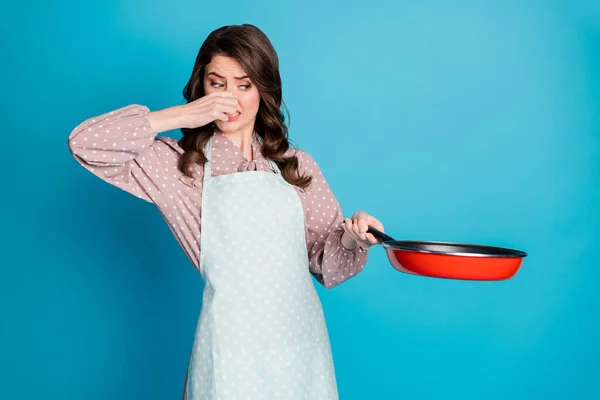 Foto di frustrata ragazza cucinare cena friggere pasto cotto troppo odore puzza terribile chiudere coperchio mani naso indossare stile elegante vestiti alla moda isolato su sfondo di colore blu — Foto Stock