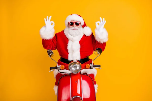 Porträtt av hans han trevlig säker glad lycklig Santa ridning moped visar dubbel ok-tecken annons vintersäsong rabatt isolerad ljus levande glans levande gul färg bakgrund — Stockfoto