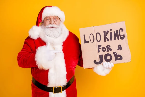 Portrait of his he nice experienced white-haired Santa holding in hands demonstrating paper card promo looking job industry finance crisis isolated bright vivid shine vibrant yellow color background