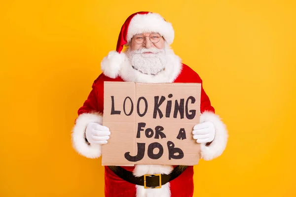 Portrait of his he nice cheerful confident experienced white-haired Santa holding in hands paper card promo seeking job occupation isolated bright vivid shine vibrant yellow color background