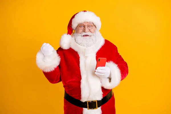 兴奋的灰白胡子头发桑塔爪用智能手机举起拳头庆祝圣诞节快乐的冬青彩票胜利头戴帽子头戴孤立的明亮色彩背景 — 图库照片