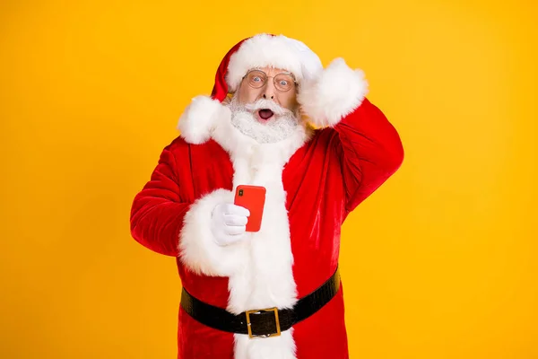O nie, wysyłam gratulacje, złe świąteczne przyjęcie. Amazed szara broda Santa Claus używać smartfona dotyk czapka ręka nosić czerwony styl kostium odizolowany jasny połysk kolor tło — Zdjęcie stockowe