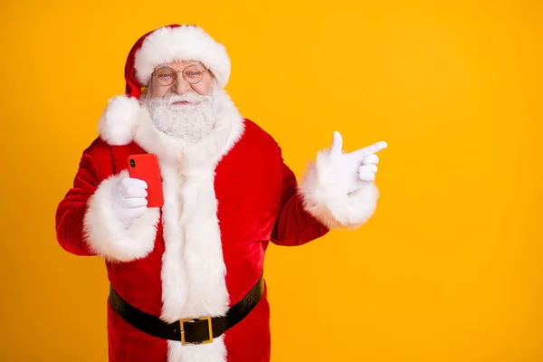 Foto av glada järnek fett Santa claus använda smartphone peka finger copyspace följa x-mas jul jul kväll annonser rabatt slitage mössa huvudbonad isolerad ljus glans färg bakgrund — Stockfoto