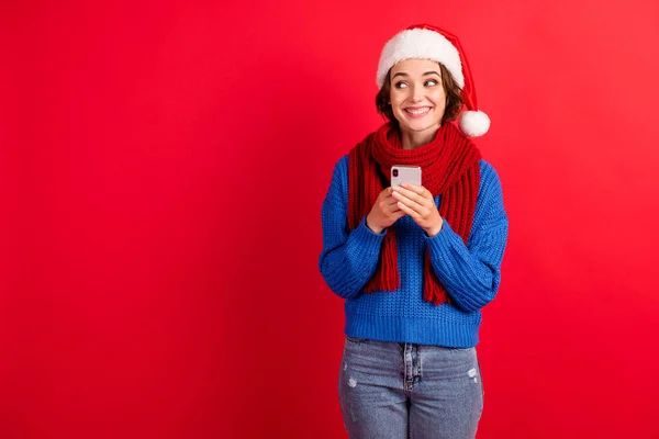 Aufgeregt Mädchen in Santa Claus Kopfbedeckung Mütze verwenden Smartphone Copyspace genießen x-Christmas Wunder Fee Rabatte tragen blau gestrickte Pullover Jeans isoliert hellen Glanz Farbe Hintergrund — Stockfoto