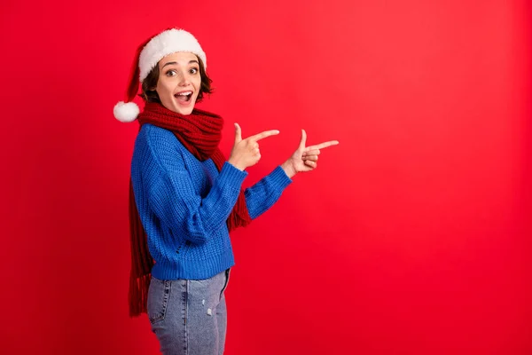 If you want christmas discount go here. Shocked girl santa claus headwear point finger copyspace indicate adverts wear blue knitted sweater denim jeans isolated bright shine color background — Stock Photo, Image