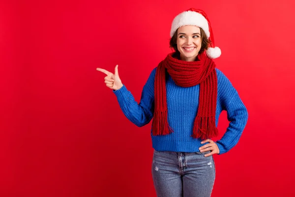 Foto gadis positif di santa claus headwear point finger copyspace menunjukkan Natal musim tradisi diskon memakai pullover biru denim terisolasi warna cerah latar belakang — Stok Foto