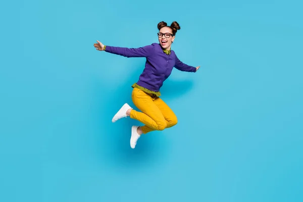 Full body profile photo of crazy lady two buns jump high celebrate vacation holidays weekend rejoicing spread arms wear specs shirt pullover pants isolated blue color background — Stock Photo, Image