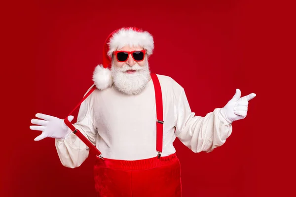 Portrait of his he nice handsome cheerful cheery bearded Santa demonstrating copy space novelty advice pulling suspender having fun isolated bright vivid shine vibrant red color background — Stock Photo, Image