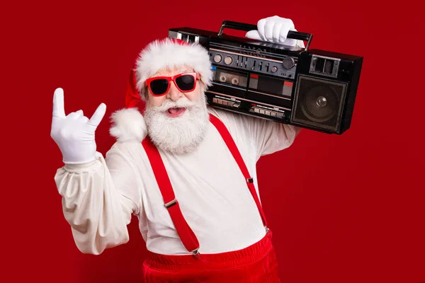 Close-up portrait of nice handsome cool cheery bearded Santa father hipster carrying boombox having fun show horn sign heavy metal celebratory isolated bright vivid shine vibrant red color background — Stock Photo, Image