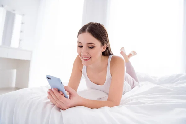 Primeros planos foto de la casa bonita esposa joven dama sostener las manos telefónicas escribir blog red social post acostado cama acogedora freelancer cuarentena ropa blanca soleado mañana estancia en casa habitación interior — Foto de Stock