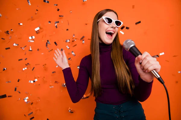 Foto de la joven hipster chica cool disfrutar de fiesta de karaoke cantar canción micrófono desgaste violeta jersey púrpura aislado sobre confeti volar caída brillante brillo color fondo —  Fotos de Stock