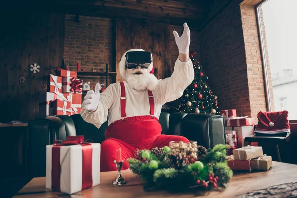 Photo de choqué barbe grise accro santa claus assis canapé joueur jouer jeu de simulation 3d utiliser des lunettes porter casquette rouge casque dans la maison à l'intérieur x-Noël décoration de Noël — Photo