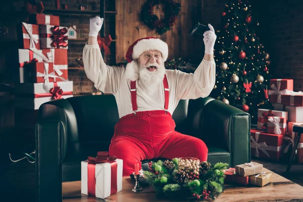 Foto de louco viciado em barba cinza santa claus sentar ouch tem engraçado x-mas noel festa jogar vídeo game ganhar levantar punhos desgaste chapéu vermelho headwear em casa em casa dentro de casa com Natal evergreen árvore decoração — Fotografia de Stock