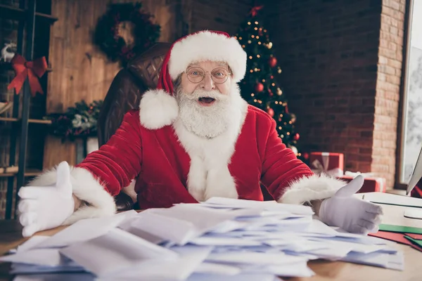 Crazy santa claus verbaasd onder de indruk velen ontvangen verlanglijstje brieven tonen zitten tafel dragen pet hoofddeksels in huis binnen met kerst x-mas verlichting decoratie — Stockfoto