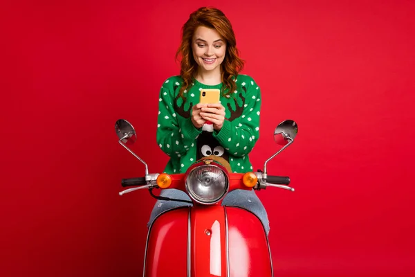 Foto portrét řidiče skútru drží telefon ve dvou rukou na sobě ošklivé zelené svetr svetr izolované na jasně červené barevné pozadí — Stock fotografie