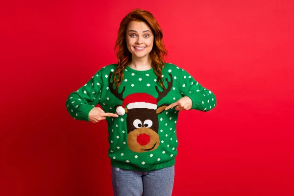 Photo portrait of happy girl pointing two fingers at christmas sweater ornament isolated on bright red colored background — Stock Photo, Image