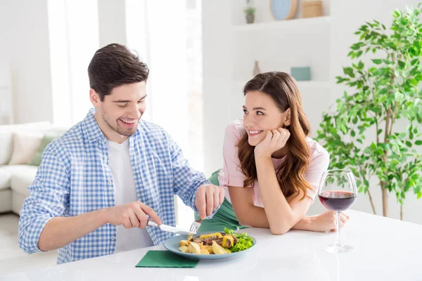 Portret van twee mooie aantrekkelijke voorzichtige vrolijke vrolijke getrouwde echtgenoten man eten smakelijke lekker huiselijke maaltijd genieten van thuis vrijetijdsbesteding in licht wit interieur keuken huis appartement — Stockfoto