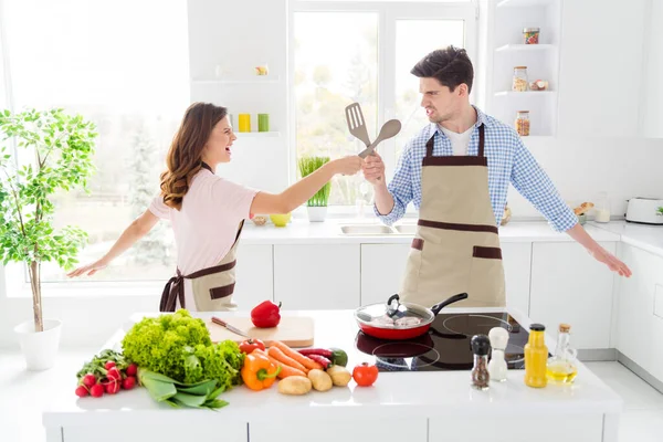 Porträtt av två trevliga attraktiva positiva roliga glada glada glada makar matlagning hemlagad mat ha kul slåss i ljus vit interiör kök hus lägenhet inomhus — Stockfoto