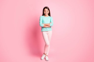 Full body size photo of pretty sweet small hispanic lady long hairstyle crossed hands self-assured look cool wear turquoise sweatshirt pants sneakers isolated pink color background clipart