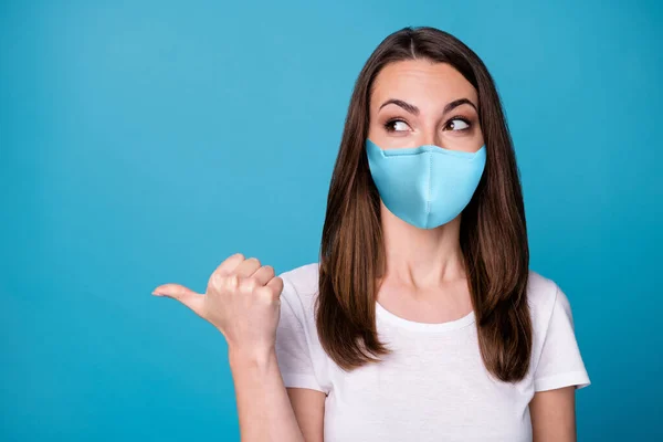 Retrato de positivo alegre menina ponto polegar dedo copyspace demonstrar covid anúncios promoção desgaste boa aparência roupas máscara médica isolado sobre azul cor de fundo — Fotografia de Stock