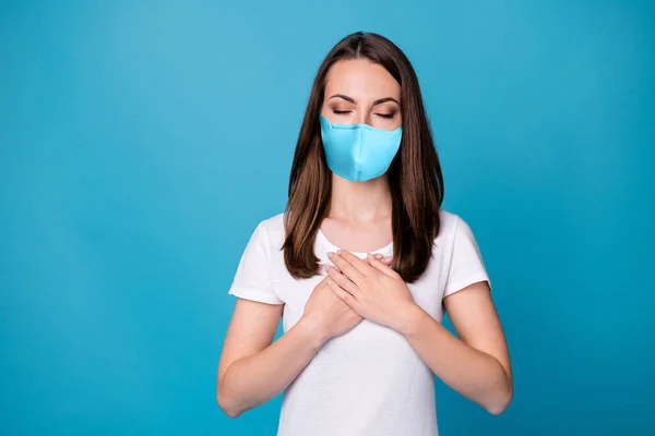 Φωτογραφία της ήρεμης ειρηνικής κορίτσι θέσει τα χέρια στήθος θαυμάσει ανάπαυση χαλαρώστε covid λοίμωξη προστασία της υγείας φορούν ιατρική μάσκα casual στυλ ρούχα απομονωμένο μπλε χρώμα φόντο — Φωτογραφία Αρχείου