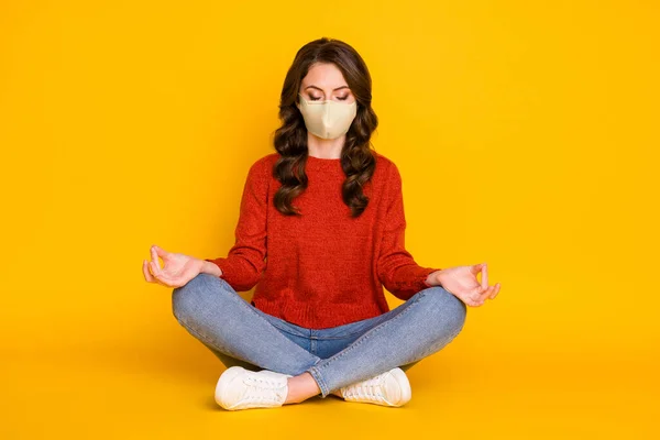 Retrato dela ela agradável atraente sonhador focado menina de cabelos ondulados sentado na posição de lótus meditando isolado no brilho brilhante cor amarela fundo desgaste máscara médica — Fotografia de Stock