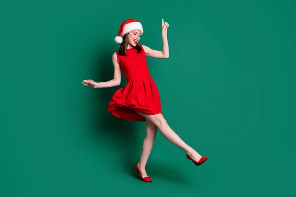 Фотографія повного тіла милої привабливої леді новорічної вечірки святковий гарний настрій танцює дискотека молоді популярна пісня носіння шапки Санта червона міні-сукня костюм стилети ізольовані зелений колір фону — стокове фото