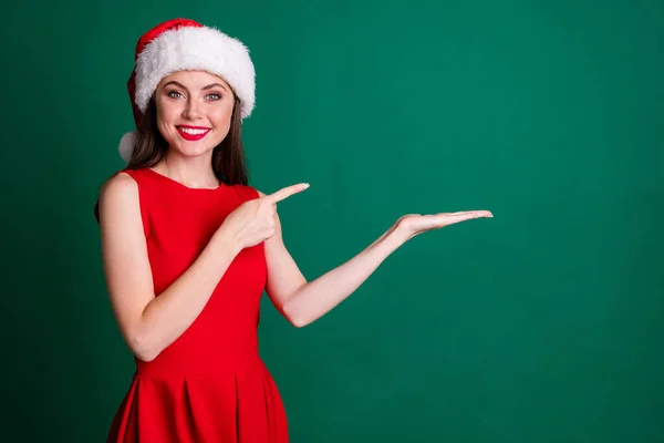 Фото чарівної привабливої леді тримає відкриту руку долоні прямий продаж пальців зі знижкою декор новорічний пригода продукт одягати сніг дівчина костюм сукня Санта-капсула ізольований зелений колір фону — стокове фото