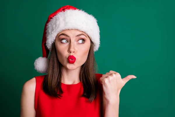 Clsoeup foto de atraente encantador senhora dedo polegar direto olhar interessado lado vazio espaço novidade enviar beijos desgaste vermelho neve menina vestido fofo santa cap isolado cor verde fundo — Fotografia de Stock