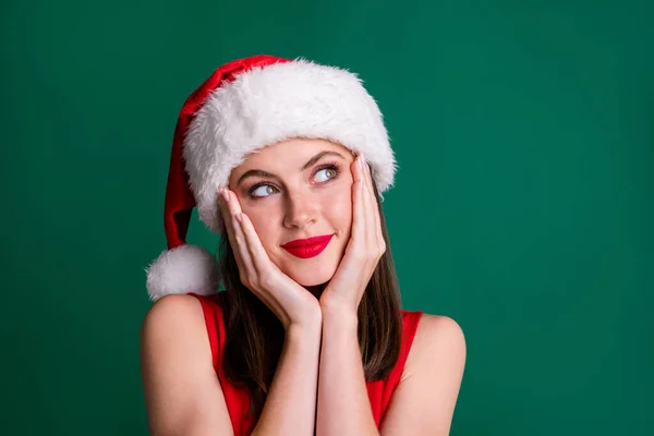 Primo piano foto di attraente affascinante x-mas signora rossetto rosso guardare lato vuoto spazio braccia zigomi faccia sognatore atmosfera aspettare miracolo indossare Santa cap isolato verde pastello colore sfondo — Foto Stock