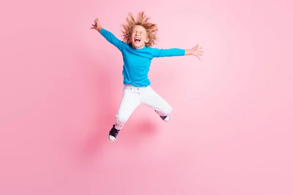 Plná délka fotografie malého dítěte skok zavřít oči otevřená ústa nosit modré rolák kalhoty tenisky izolované pastel růžová barva pozadí — Stock fotografie