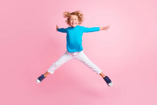 Фотографія повної довжини маленьких дитячих стрибків ноги зірки носять сині штани-факели кросівки ізольовані пастельно-рожевий кольоровий фон — стокове фото