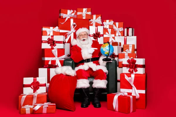 Tam boy vücut ölçüsü yakışıklı şaşırmış şişman Noel Baba sandalye yığınında oturuyor hediyeler yolluyor ülke haritası rota rotası nakliyesi izole parlak parlak parlak parlak parlak parlak parlak arka plan — Stok fotoğraf