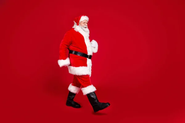 Volledige lengte lichaamsgrootte profiel zijaanzicht van zijn he nice aantrekkelijke aantrekkelijke vrolijke vrolijke Santa vader wandelen Noordpool geïsoleerde heldere levendige glans levendige rode kleur achtergrond — Stockfoto
