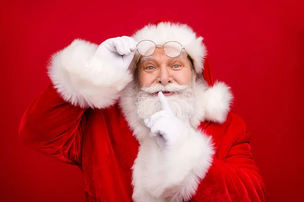 Foto van gepensioneerde oude man grijze baard af te nemen bril vinger cover lippen opgewonden wil verrassing kind dragen x-mas kostuum witte handschoenen jas bril hoofddeksel geïsoleerde rode kleur achtergrond — Stockfoto