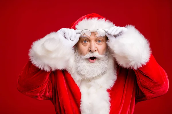 Zdjęcie emeryta starzec szary broda podekscytowany wygląd trzymać okulary otwarte usta szok zobacz kobieta sam strój nosić Santa strój płaszcz okulary głowy odizolowany czerwony kolor tło — Zdjęcie stockowe