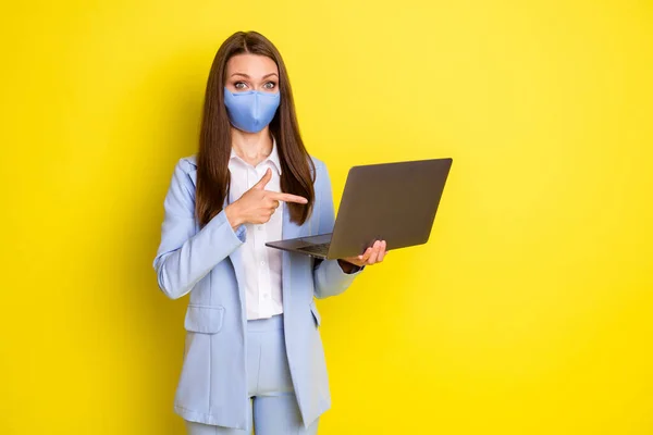 Σοκαρισμένη οικονομολόγος κορίτσι στην αναπνευστική μάσκα εργασίας απομακρυσμένο σημείο laptop δάχτυλο παρουσιάσει covid ειδήσεις καραντίνα φορούν μπλε σακάκι παντελόνι παντελόνι παντελόνι απομονωμένο φωτεινό λαμπερό χρώμα φόντο — Φωτογραφία Αρχείου