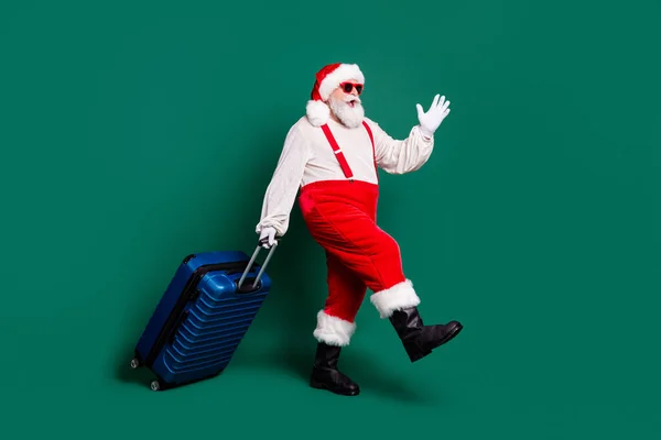 Pleine longueur profil taille du corps vue de côté de beau barbu funky gai en surpoids graisse Père Noël portant valise avion vol voler départ voyage avoir plaisir isolé couleur verte arrière-plan — Photo